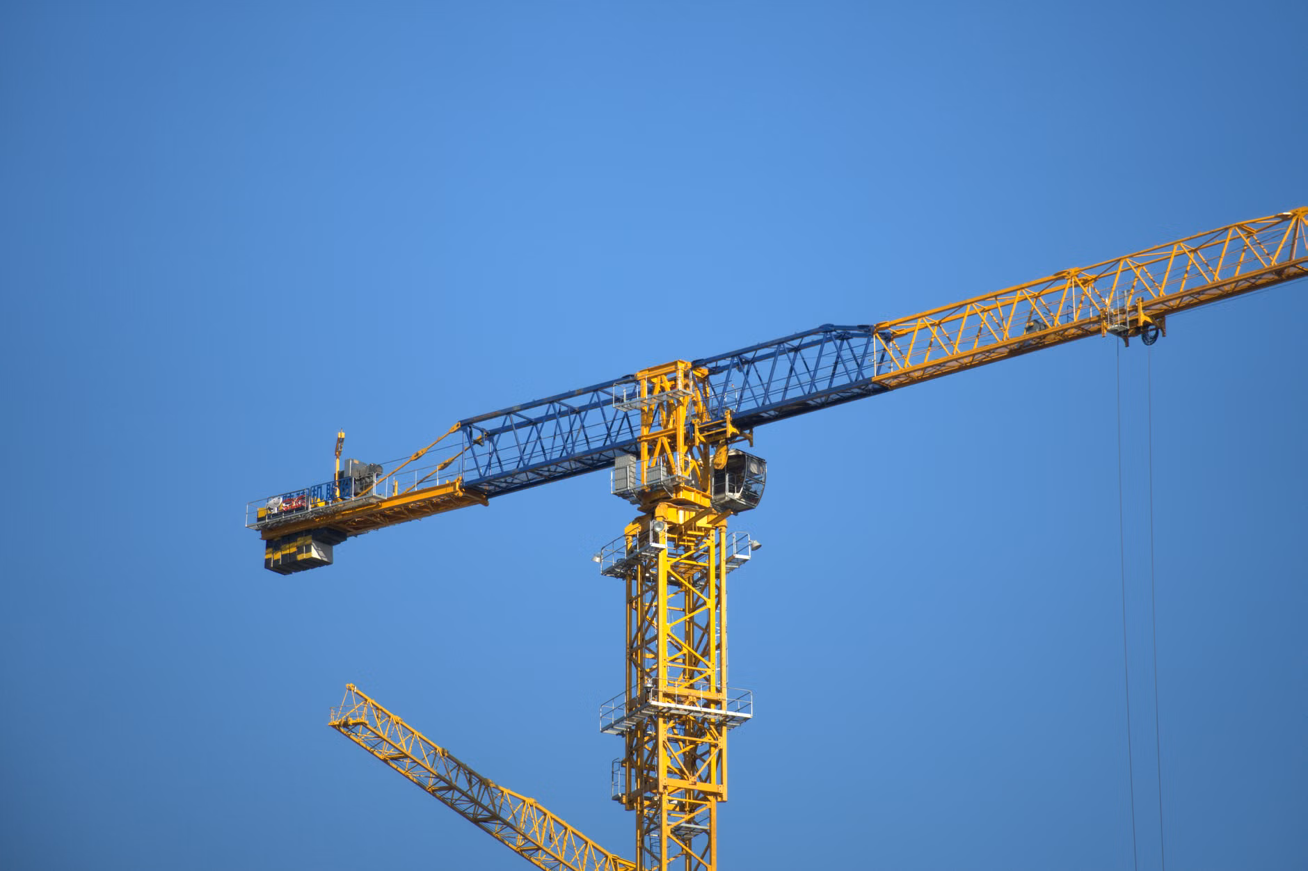 Gros plan d'une grue à tour jaune avec un fond de ciel bleu clair.