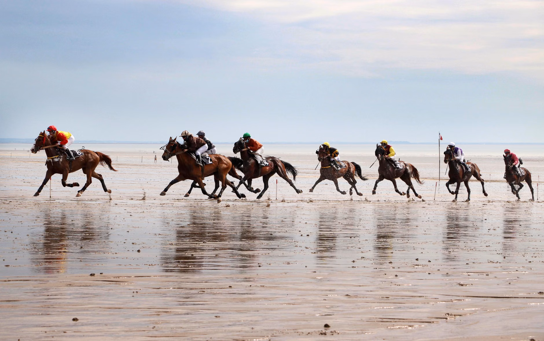 Course de chevaux excitante sur la plage de Jullouville, mettant en avant des cavaliers et des chevaux en action.