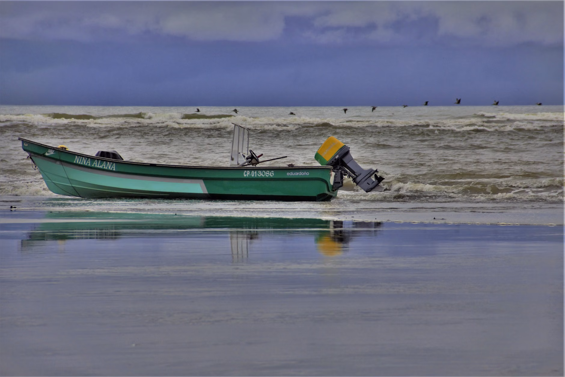 A fishing boat rests on the shore with a serene sea backdrop in Buenaventura, Colombia.
