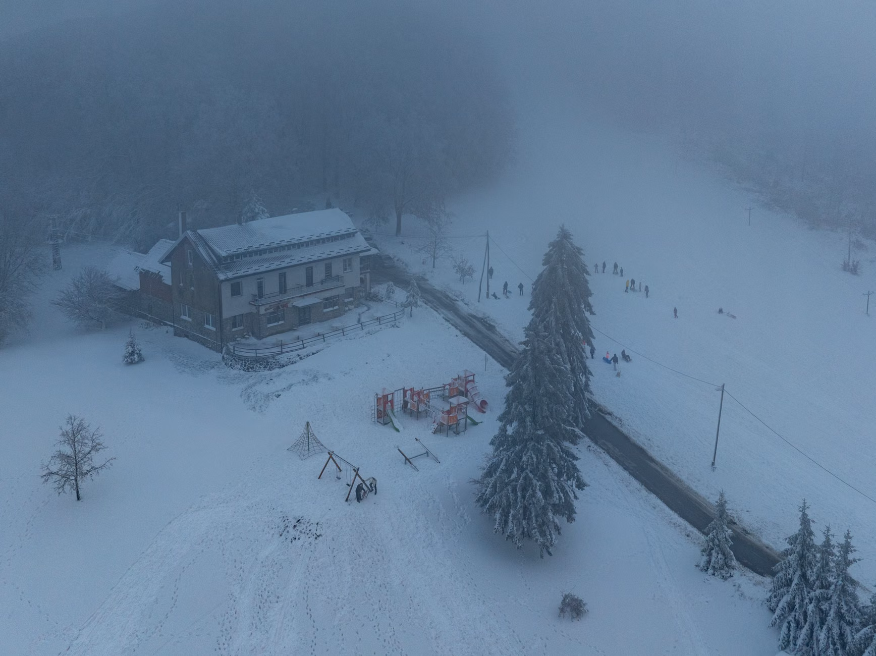 Aerial view of a snowy winter landscape in Daruvar, Croatia with scattered trees and a house.