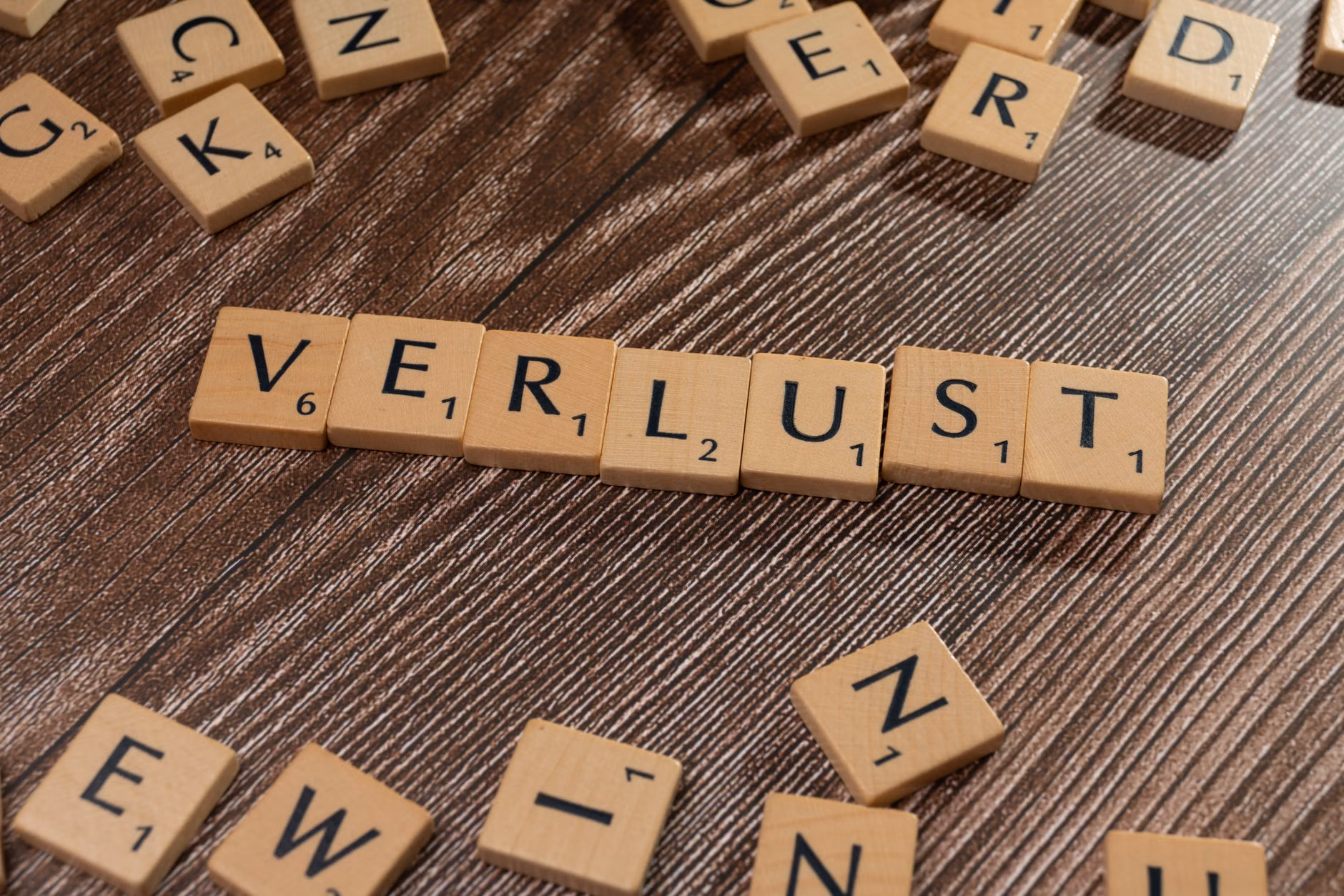 Scrabble-Steine, die 'Verlust' auf einem Holztisch buchstabieren, symbolisieren Verlust oder finanziellen Kontext.