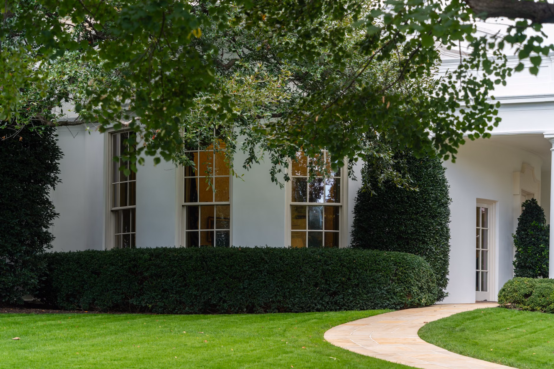Una bella casa suburbana con giardino curato e vegetazione lussureggiante, creando un'atmosfera serena.