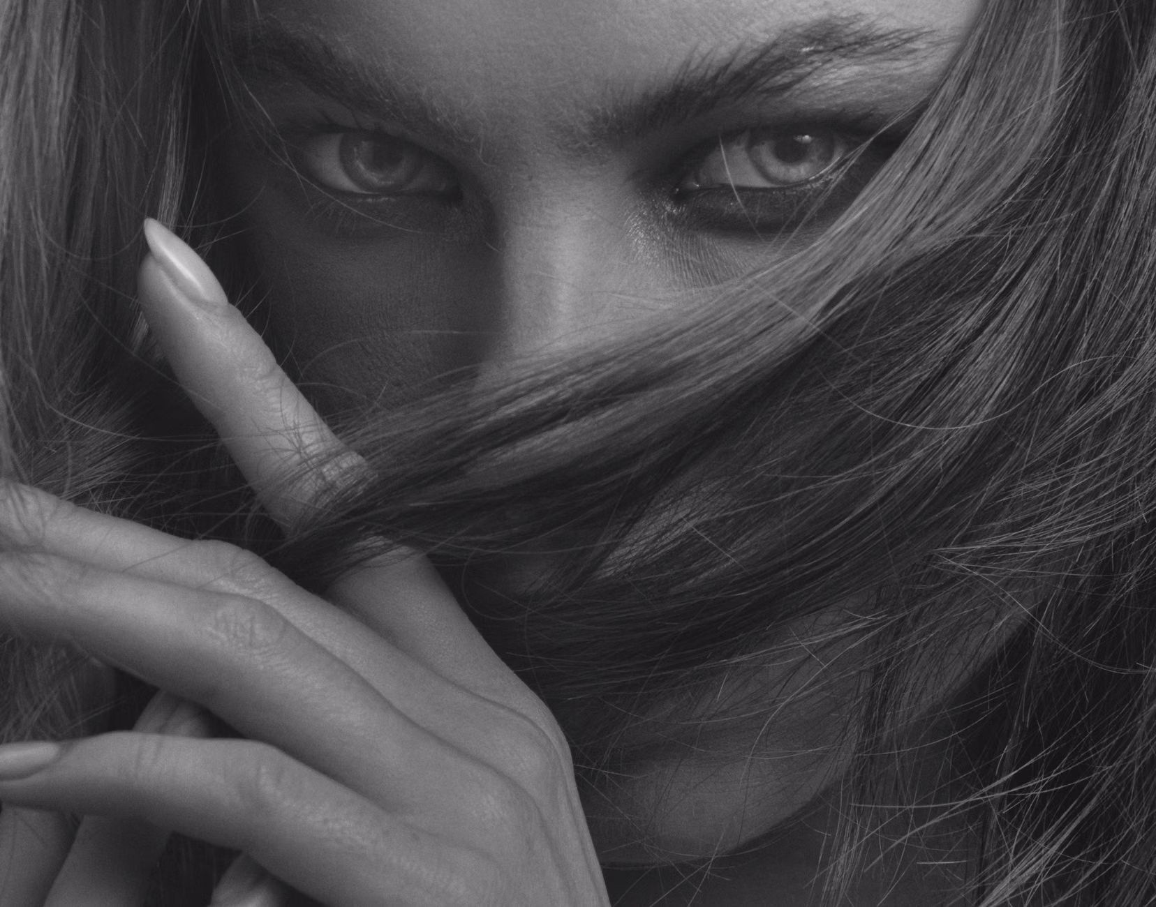 Captivating black and white close-up portrait of a woman with intense gaze and hair partially covering her face.