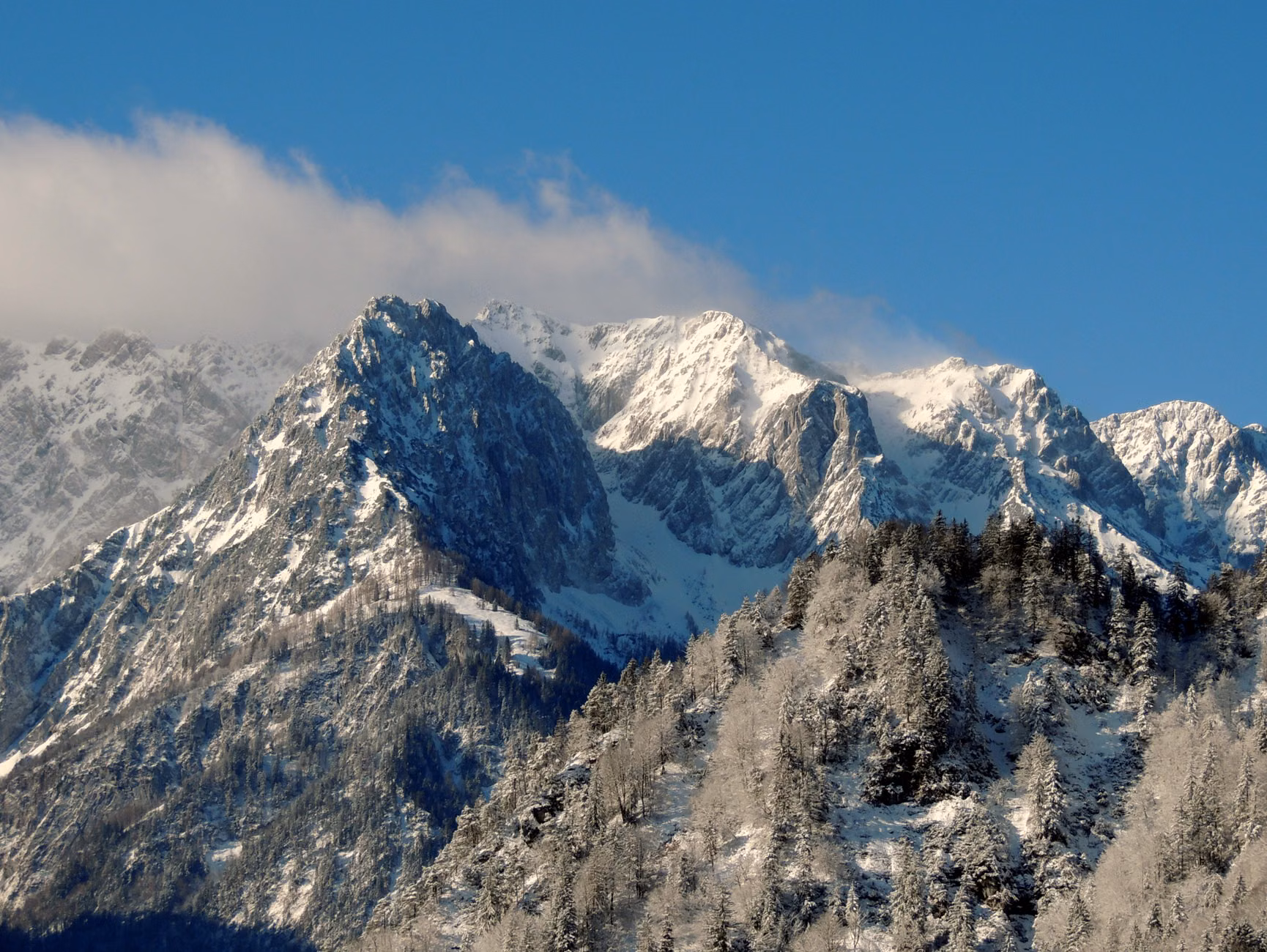 Dramatische schneebedeckte Berge unter einem klaren blauen Himmel, die die ruhige Schönheit des Winters in den Alpen festhalten.
