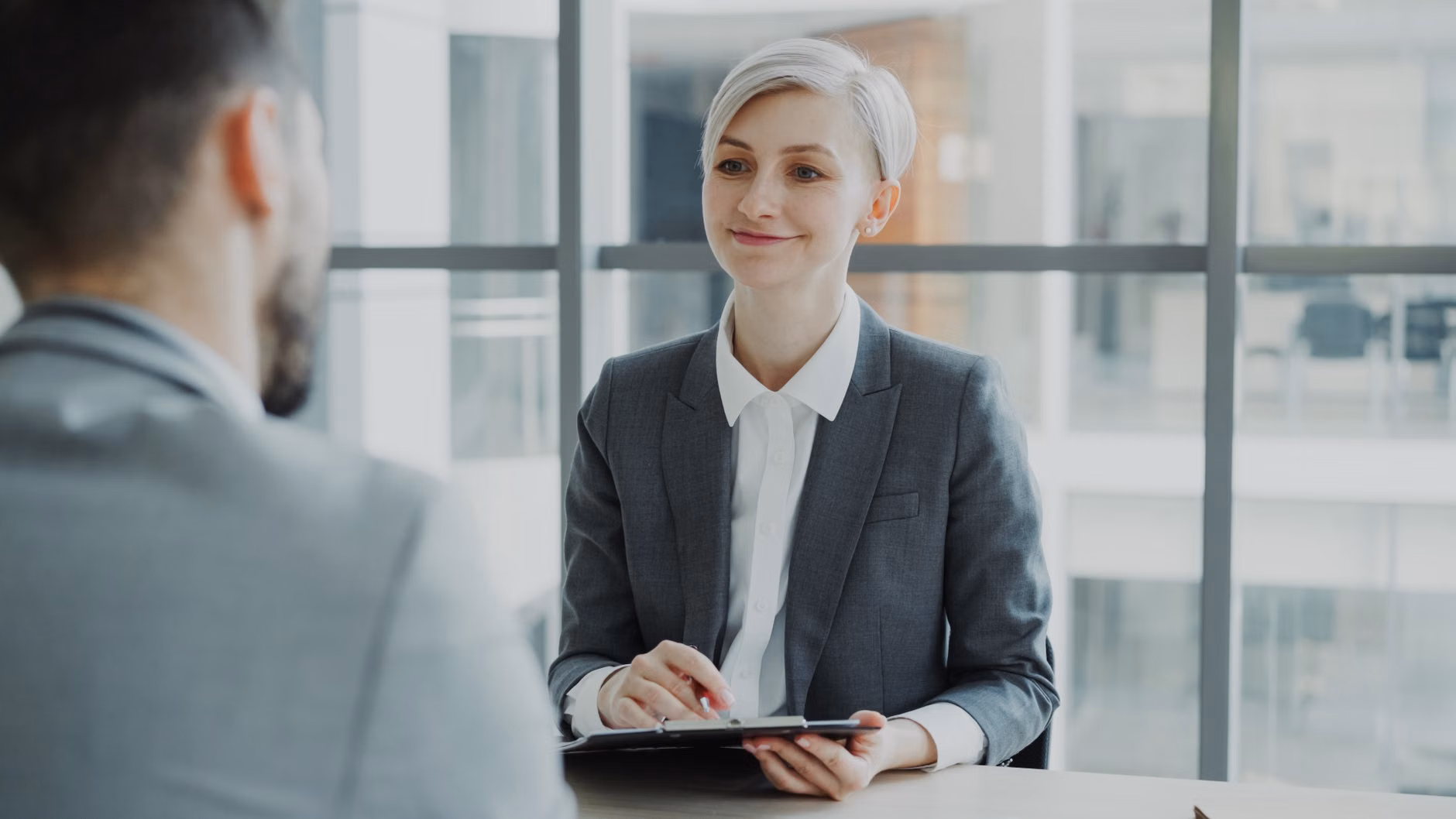 Femme confiante interviewant un candidat dans un bureau moderne. Idéal pour des visuels d'affaires et de ressources humaines.