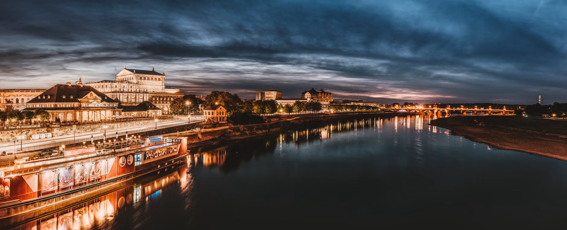 Beeindruckende Dämmerungsansicht einer beleuchteten Stadtansicht, die sich auf einem Fluss spiegelt und die Schönheit der Stadt zeigt.