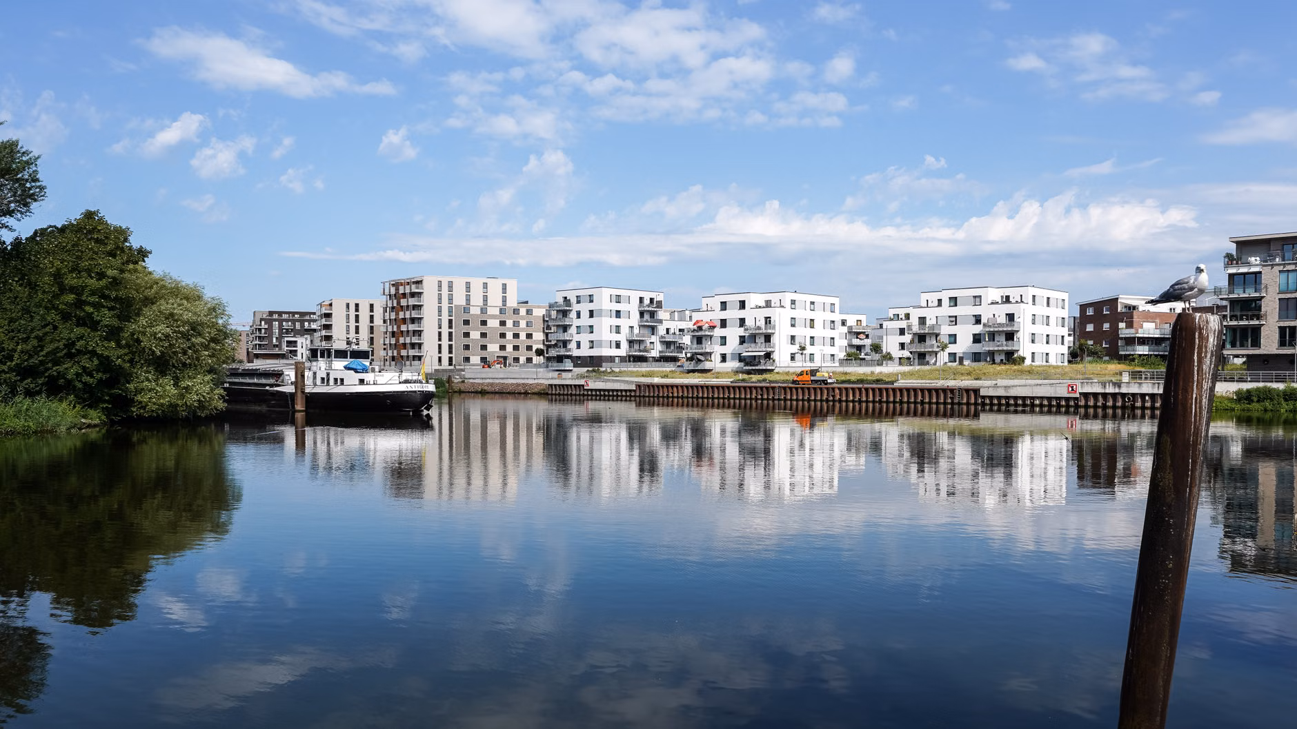 Malerische Ansicht moderner Apartments, die sich in einem ruhigen Fluss in Geesthacht spiegeln.