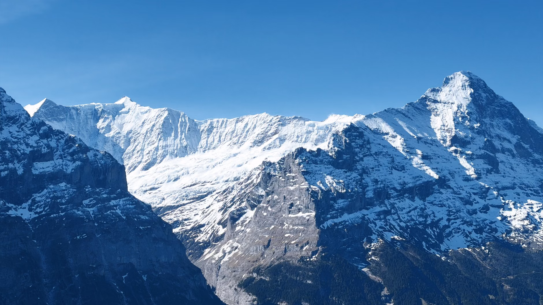 Atemberaubender Blick auf schneebedeckte Alpengipfel unter klarem Himmel in der Schweiz.