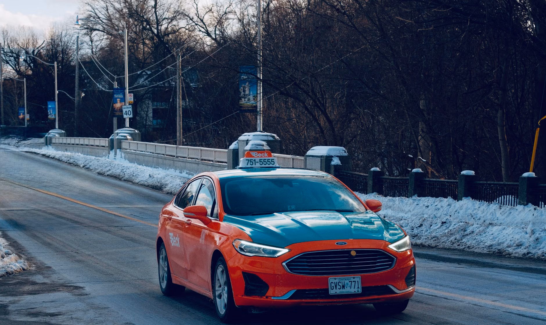 Ein Taxi mit auffälliger Lackierung fährt über eine verschneite Brücke in Toronto und fängt so die Essenz des Reisens im Winter ein.