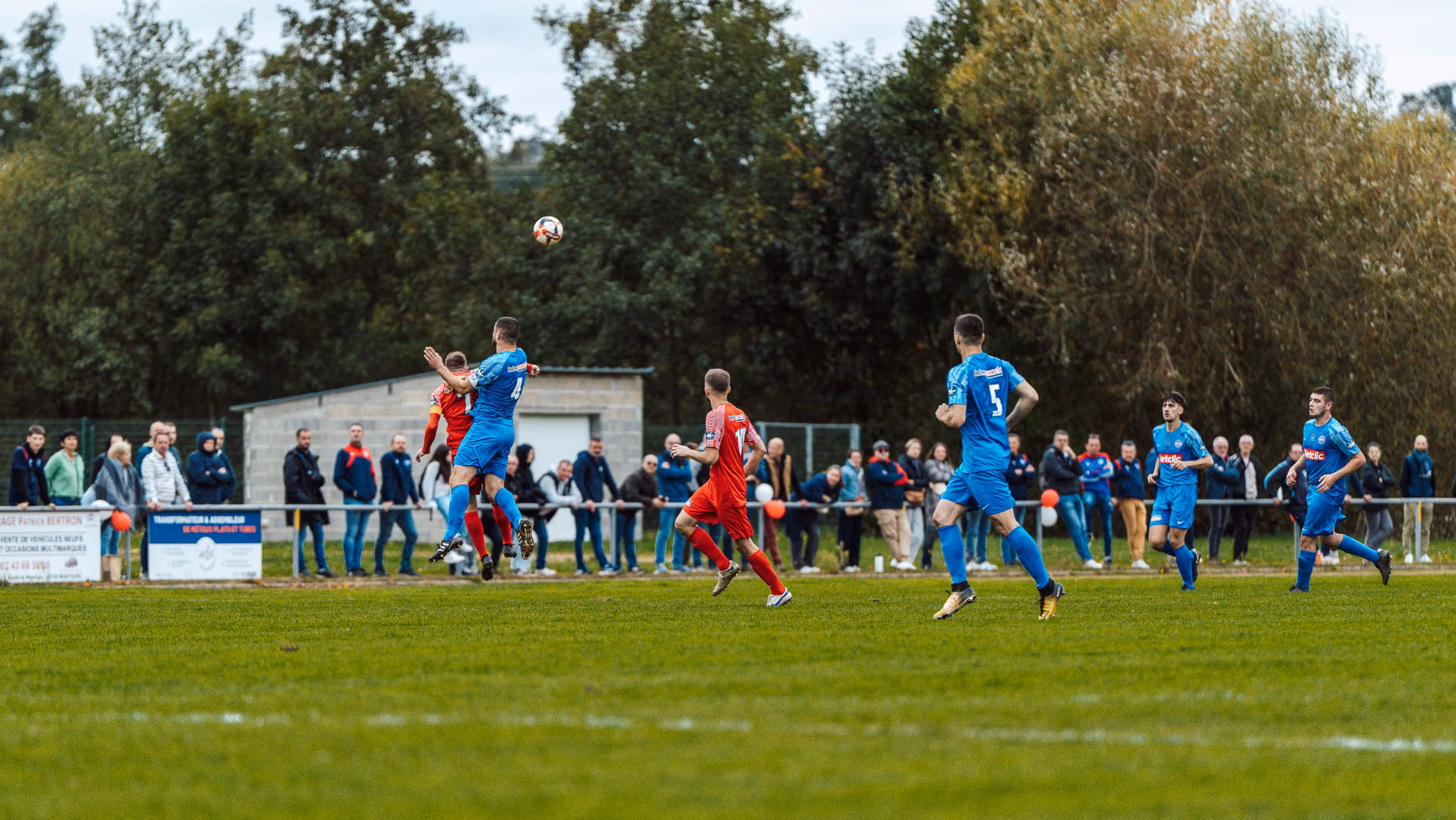 Des joueurs en bleu et rouge s'affrontent intensément sur un terrain de football en France, capturant l'esprit du jeu.