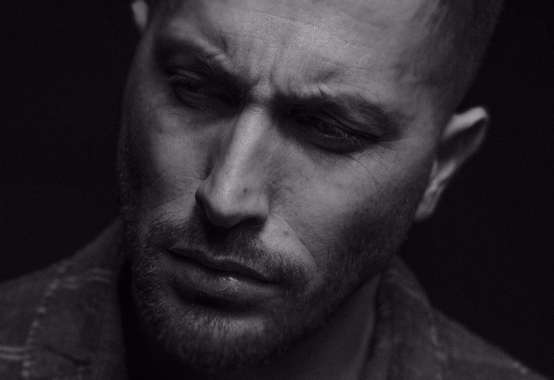 Close-up monochrome portrait of a man with facial hair, expressing deep thought.